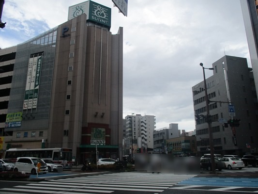 信号の手前で待っておくと、サニーと右側に弊社の店舗が見えます。（緑の看板の2階建ての建物です）